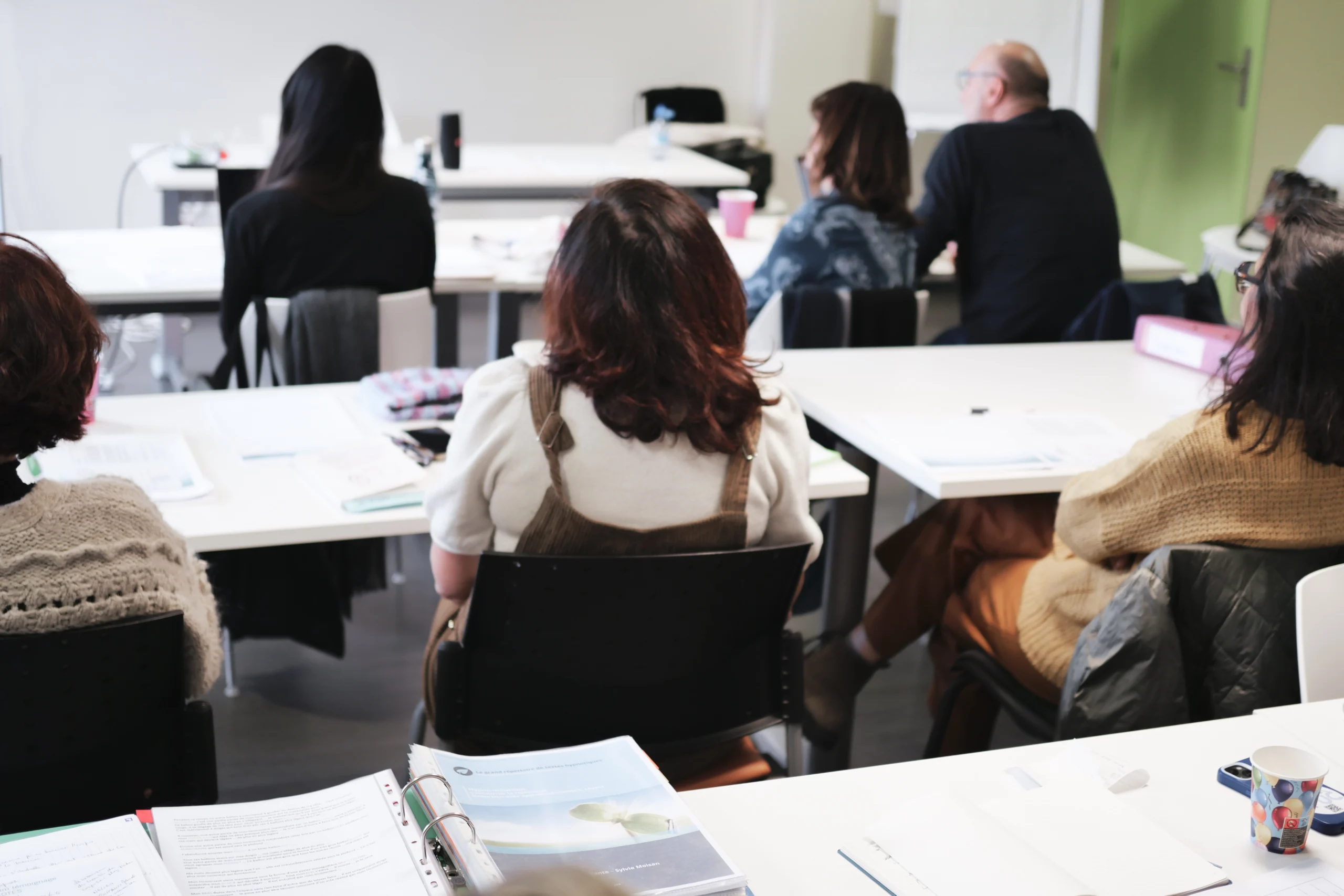 Les élèves de la promotion de dos écoutant attentivement.